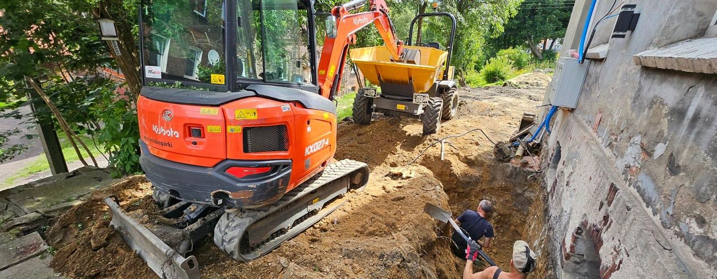 Wykop pod izolację przeciwwilgociową fundamentów kamienicy, prace ziemne minikoparką